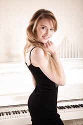 Horny teen Tempe loses her black dress and poses in front of a piano