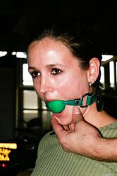 Clothed female is left alone in a chair after being ball gagged and tied up