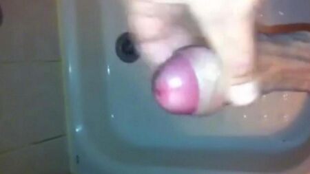 The kid stands in the shower and jerks off the penis with his hand mining the end